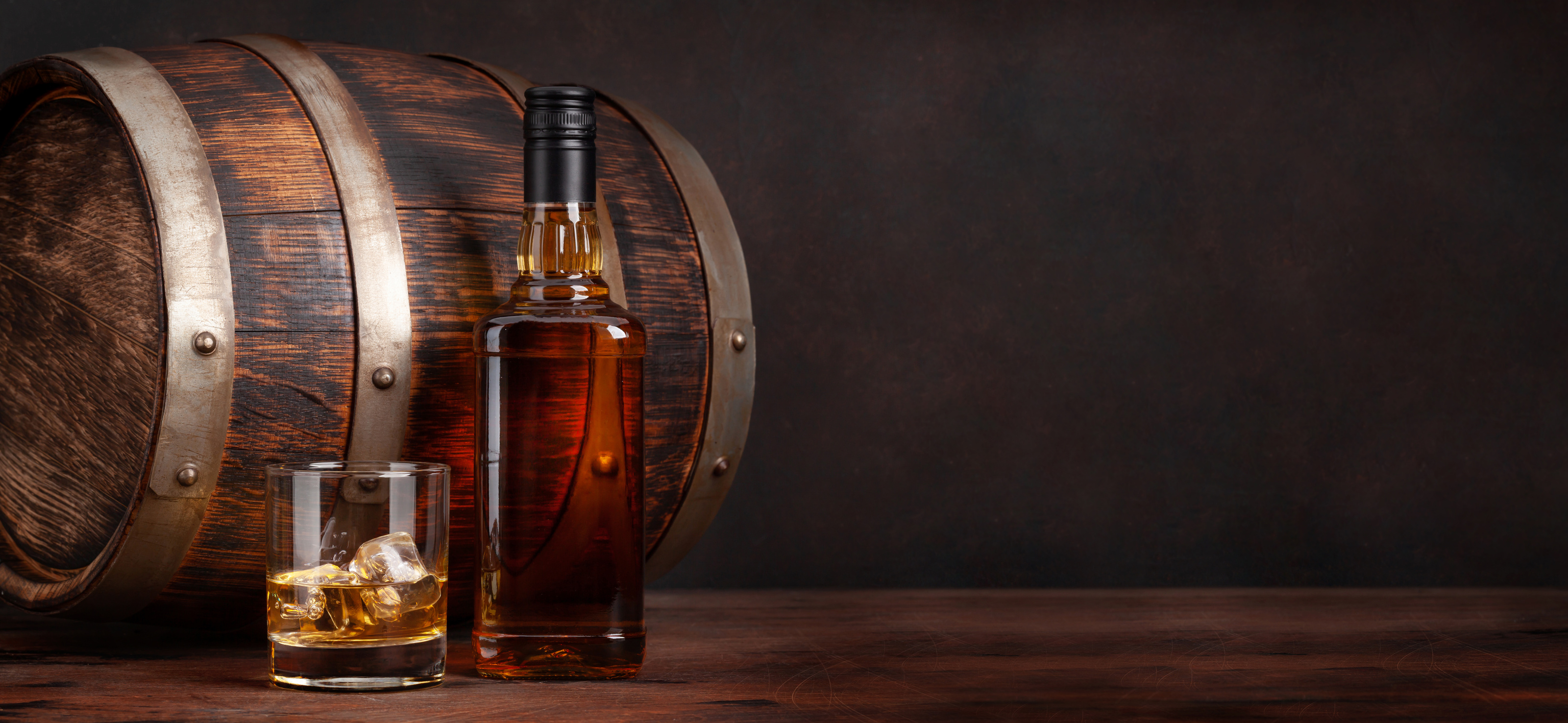 Scotch whiskey bottle, glass and old barrel